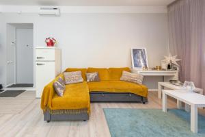un soggiorno con divano giallo in una camera di Main street apartments SELF CHECK IN 24/7 by H&H a Vilnius
