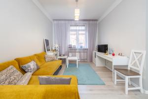 un soggiorno con divano giallo e scrivania di Main street apartments SELF CHECK IN 24/7 by H&H a Vilnius