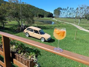 a glass of orange juice sitting on a balcony with a car at Fazenda Serramar in Palhoça