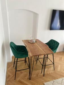 a wooden table with green chairs in a room at Schiller Rooms in Sibiu