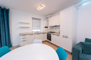 a kitchen with white cabinets and a table and chairs at ART Apartment III in Târgu-Mureş