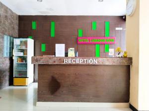 um balcão de recepção com quadrados verdes na parede em Hotel Labuhan Raya em Medan
