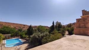 een zwembad in het midden van een woestijn met bomen bij Hotel camping le Soleil Tinghir in Tinerhir