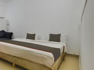 - une chambre avec un grand lit aux murs blancs dans l'établissement Collection O Goa Savera Holiday Homes, à Nerul