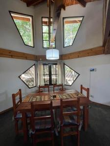 a dining room with a wooden table and windows at Aljabas in San Martín de los Andes