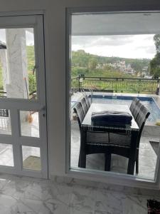 a table and chairs on a balcony with a glass door at Puncak villa in Puncak