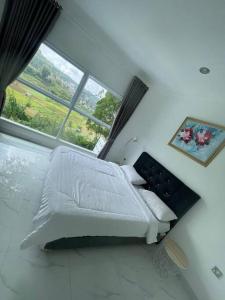 a white bed in a room with a large window at Puncak villa in Puncak +8 photos