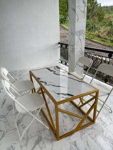 a glass table and two chairs on a balcony at Puncak villa in Puncak