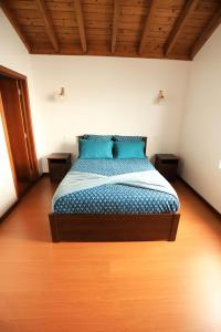 a bedroom with a bed with blue sheets and wooden floors at The Blue Eden in São João