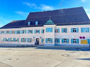 un grand bâtiment blanc avec un toit noir dans l'établissement Gasthof Zur Post - Inning, à Inning am Ammersee