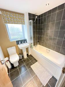 a bathroom with a tub and a toilet and a sink at Luxury 3 Bedroom House With FREE Parking in Dinnington