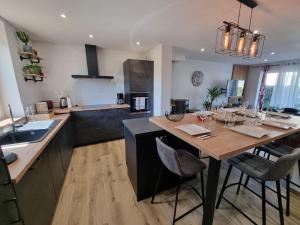 una cocina con una gran mesa de madera con sillas en La Tanière de la baie, en Le Val-Saint-Père