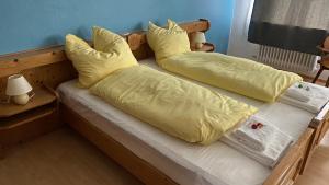 two beds with yellow sheets and pillows in a room at Gasthof Zur Post - Inning in Inning am Ammersee