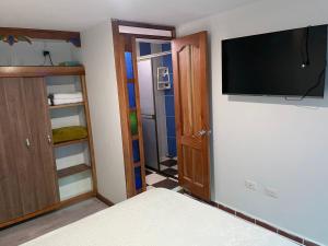 1 dormitorio con TV en la pared y armario en Habitación La Amelia, en Jericó