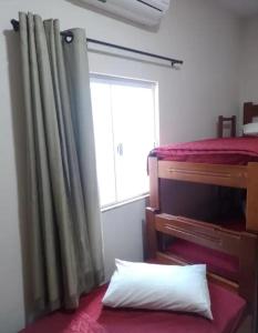 a bedroom with a bed and a window and a pillow at Pousada Mundo Novo in Aparecida