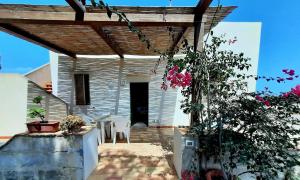 un porche de una casa con sillas y flores en Villetta Maestrale Cala Azzurra Favignana en Favignana