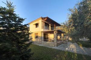 a large yellow house with a balcony and trees at Villa Bellissimo in Skala Potamias