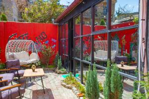 a patio with tables and chairs and a red wall at Hotel Homeland in Batumi