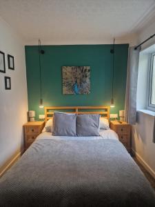 1 dormitorio con 1 cama grande y pared verde en Cosy Self Contained Annexe en Bodmin