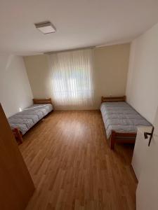 two beds in a large room with wooden floors at Vikendica Lazić in Ljubovija