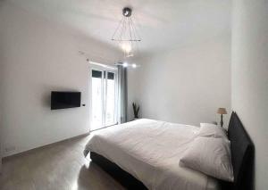 a white bedroom with a large bed and a television at Enjoy in Lido di Ostia
