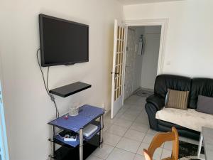 a living room with a couch and a flat screen tv at Chaleureux logement familial jusqu'à 6 personnes in Annemasse