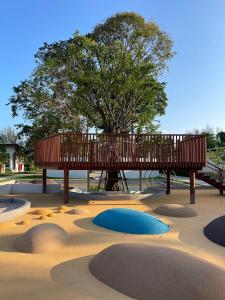 a park with a playground with a wooden deck and a tree at The Season Rayong in Ban Chamrung