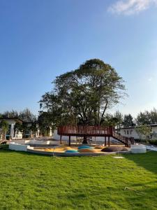 a park with a wooden bench and a tree at The Season Rayong in Ban Chamrung