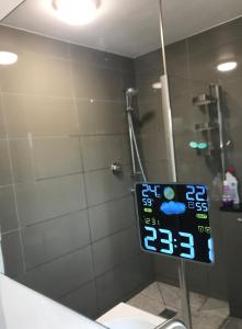 ein Badezimmer mit einer Dusche mit einer Uhr an der Wand in der Unterkunft En-suite Soft Water Air Conditioning TV NEO in London