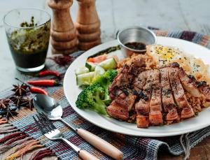 un plato de carne y brócoli en una mesa en Sandralia Hotel, en Abuja