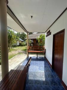 a porch with a wooden bench and a door at Pinks Bungalow in Baan Tai