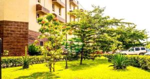 un jardín con árboles y plantas frente a un edificio en Sandralia Hotel, en Abuja