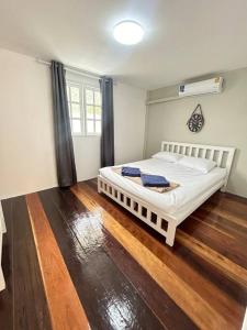 a bedroom with a large white bed with wooden floors at Townhouse nearby Klong Dao beach in Ban Mo Nae