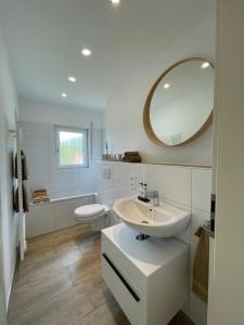a white bathroom with a sink and a mirror at Ferienwohnung zur Bitterbachschlucht in Lauf an der Pegnitz