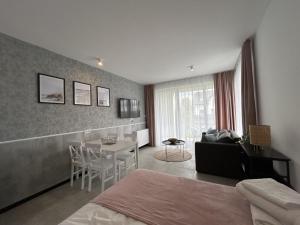 a bedroom with a bed and a table and a couch at Apartamenty Bellamaya - Kapitanska 8 in Grzybowo