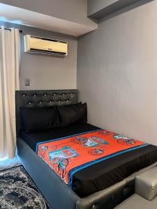 1 dormitorio con 1 cama con manta naranja en J&J Staycation at Grass Residence, en Manila