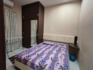 a bedroom with a bed with a purple comforter at Pulai Homestay in Ipoh