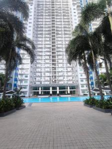 un gran edificio con palmeras delante en J&J Staycation at Grass Residence, en Manila