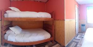 2 literas en una habitación con paredes rojas en Cabañas & Hostal Lefuco en Curacautín