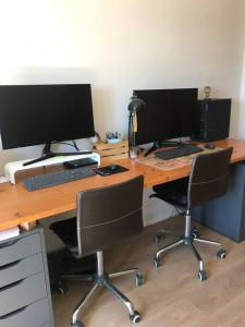 - un bureau avec 2 écrans d'ordinateur et 2 chaises dans l'établissement Piso en casa de pueblo, à Almoster