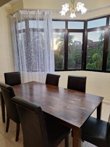 a dining room table with chairs and a large window at Seaput Srisayang in Batu Ferringhi