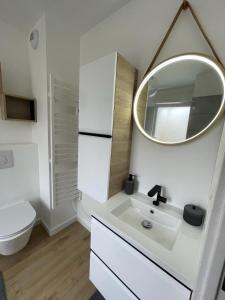 Baño blanco con lavabo y espejo en LA MAISON DE VIRGINIE, en Bénouville