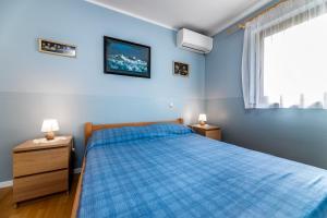 ein blaues Schlafzimmer mit einem Bett und einem Fenster in der Unterkunft Marina in Baška