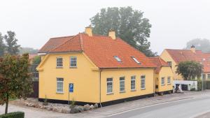 a yellow house with an orange roof on a street at Bandholm Bed and Breakfast in Bandholm