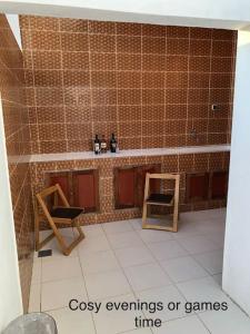 baño alicatado con 2 sillas y barra con botellas en Residence Massena, Grand-Popo in Benin, en Grand-Popo