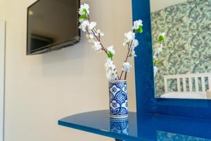 un jarrón azul y blanco con flores en una mesa en Nientemale Residence Napoli, en Pozzuoli