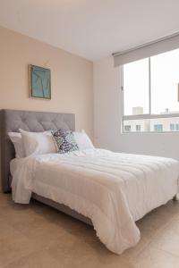 a white bedroom with a large bed with a large window at Piso 10 - Amarilo Villavicencio in Villavicencio