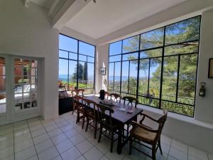 a dining room with a table and chairs and large windows at Villa Clarté Sète in Sète