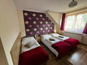 - une chambre avec 2 lits et un mur orné de fleurs dans l'établissement WYNAJEM POKOI Krościenko Halina Stołowska, à Krościenko nad Dunajcem
