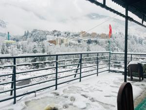 a snow covered balcony with a view of a mountain at Hotel Sliver Inn - Affordable Luxury Stay Near Mall Road in Manāli
